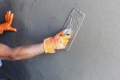 plasterer concrete worker at wall of house construction